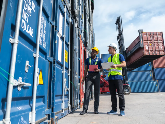 Zwei Personen stehen neben einer Reihe von Containern